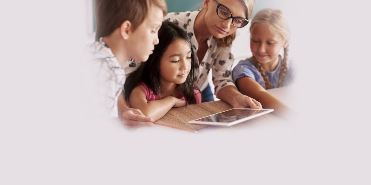 teacher working with students on a tablet device