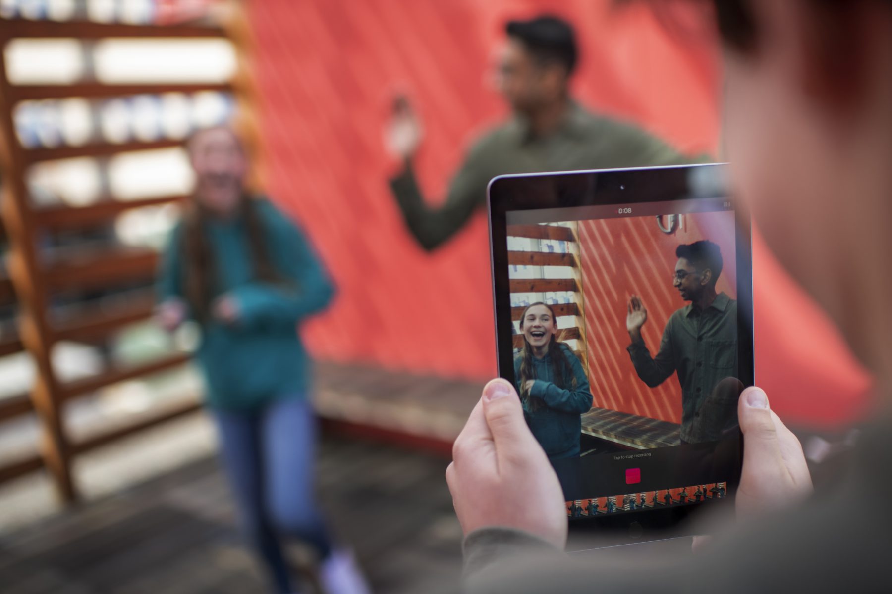 person taking a photo of two people using a tablet