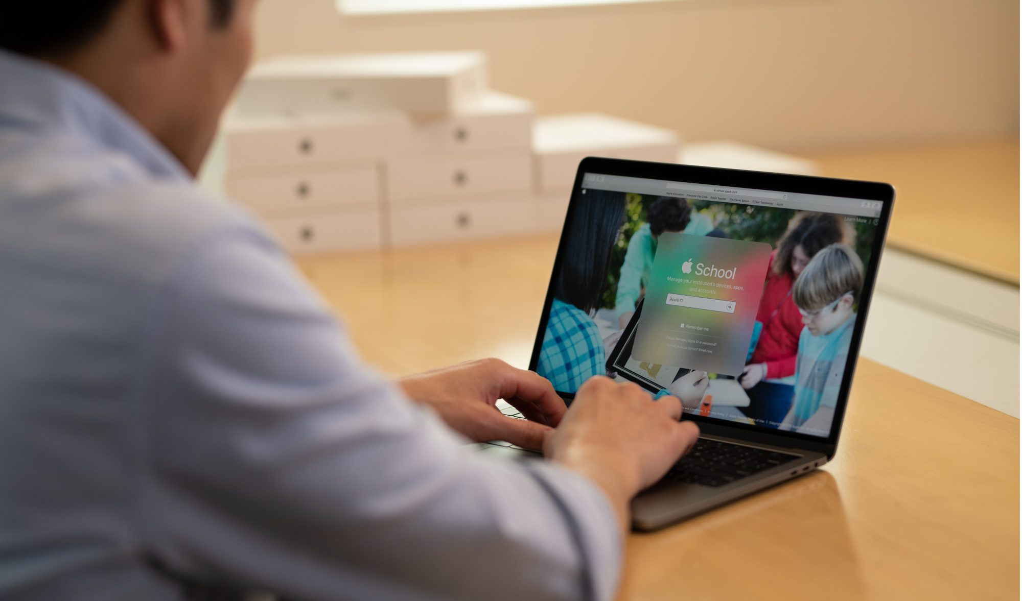 image of man behind a laptop with apple school login on screen