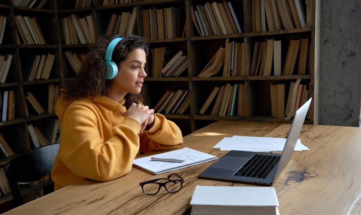 image of woman wearing headphones in front of a laptop