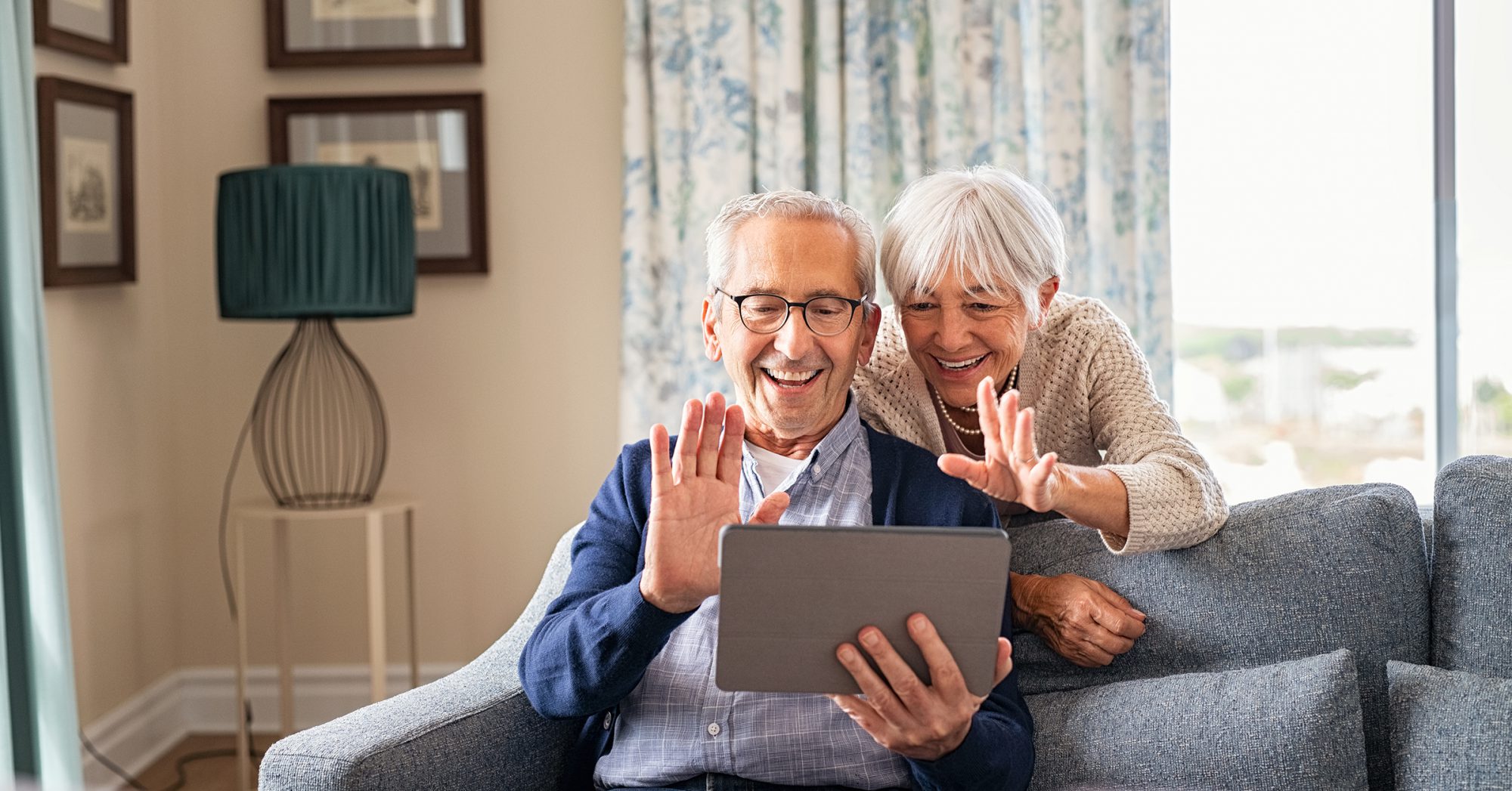 elderly couple waving to an ipad